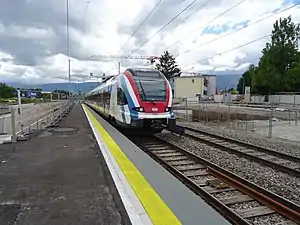 Red, white, and blue train at side platform