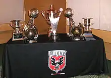 Several bronze trophies sitting on a table with the D.C. United logo
