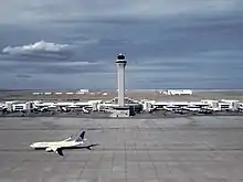 The Air Traffic Control Tower at Denver International Airport with a United Airlines Boeing 737-800 below.