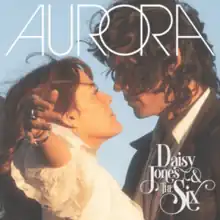 A man and woman pressed against one another looking into the other's eyes, while the woman has her arms outstretched; the album title and artist names are superimposed