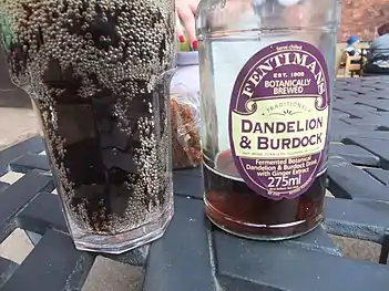 A full glass of dark carbonated drink next to a mostly-empty bottle.