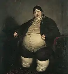Smartly dressed fat man with dark hair sitting on a chair