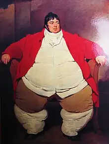 Smartly dressed fat man with dark hair and a red waistcoat, sitting on a chair