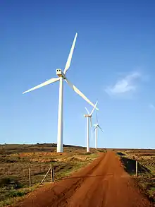 Wind turbines beside a red dirt road