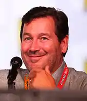 A headshot of a man seated at a microphone