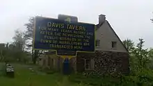 a picture of the marker with the stone tavern, flag out front, behind it