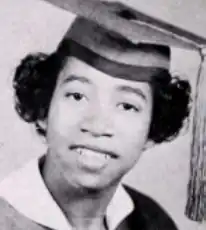 A young Black woman wearing an academic cap and gown