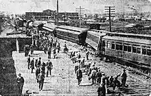 A derailed train with a crowd of people standing next to it