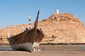 A docked dhow with Al-Ayjah Watchtower on top of the hill in the background