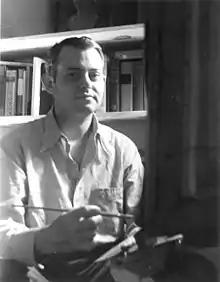 Dickson Reeder seated at easel, facing camera, 1943