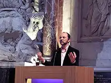 Photograph of a man speaking from a pulpit