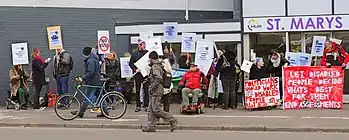 Disabled people protesting in 2015 against government policies and the inaccessibility of the assessment centre which has now been taken over by Maximus Inc. outside St Marys House, Norwich.
