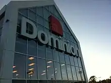 A photograph of the Dominion Store exterior, framed to show the logo.