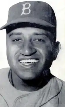 A man in a light baseball uniform and dark cap