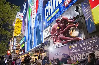 Visitors enjoy illuminated billboards, video screens and mechanized signs along the boardwalk near the Glico Man sign