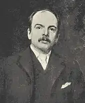 A man with a moustache and a dark suit