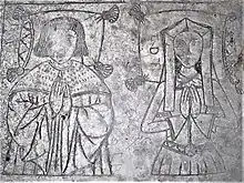 The top of the alabaster tomb. The figures are incised and traces of neillo (a black filling material) remain. They are shown half length: he wears an ermine robe, she a kennel headdress, gown, belt and gloves. The heads of both rest on tasselled pillows.