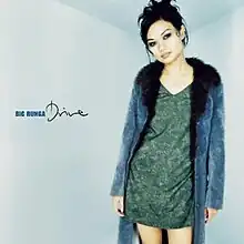 An image of Runga wearing a blue coat and green dress standing center-right in front of a blue backdrop. Her name and the album title are located to her left.