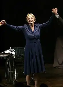 An elderly woman with her arms held aloft