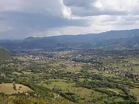 a panoramic photograph of a wide green valley with a small town in the middle distance