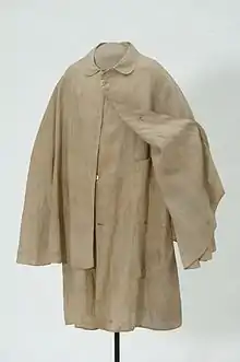 Photograph of a buff-colored duster, a front-fastened coat with a mantel over the shoulders that covers most of the arms.