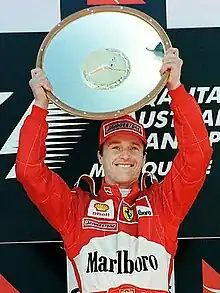 Eddie Irvine holding a trophy in both his hands after winning a race