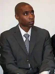 Soccer player Eddie Pope sitting while wearing a suit and looking away from the camera.