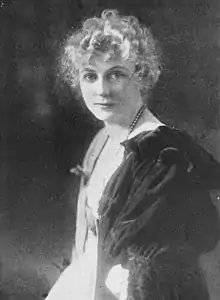 A portrait of a white woman with blond curly hair