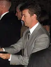 A side view of Norton in suits giving autographs