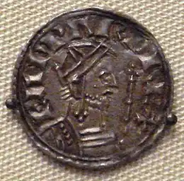  A coin depicting a bearded man facing to the right holding a sceptre, with a Latin inscription going from left to right over him