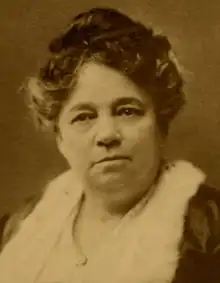 A middle-aged African-American woman, hair in an updo, wearing a dress or blouse with a wide square lacy collar.