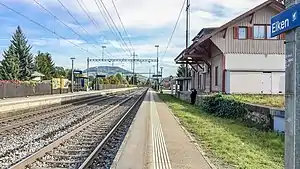 Looking down a double-track railway line with station building at right