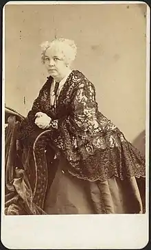 Photograph of Elizabeth Cady Stanton leaning on a piece of furniture and turning toward the camera