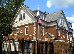 A large brick house with the flag of Iraq on a flagpole.