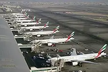View of airport tarmac with terminal building and multiple airliners parked adjacent to it.