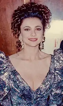 White woman with brown curly hair wearing a blue dress smiling at the 62nd Academy Awards.