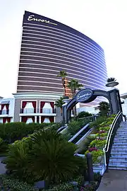 Ground-level view of a convex, curved building; the building has a complete glass facade and is light brown in color.