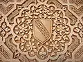 Hybrid inscription on the Alhambra walls; the Arabic Nasrid motto inscribed on the traditionally European coat of arms.