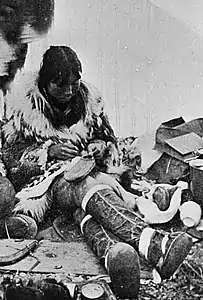 Making waterproof summer overshoes in a tent, c. 1900, Port Clarence, Alaska