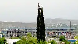 photo of stadium from outside with mountains in distance and trees in foreground