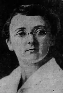 A white woman with short dark hair, wearing eyeglasses and a white lab coat