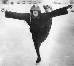 Monochrome photograph of Ethel Muckelt skating on an ice rink in 1924. She is shown with her leg behind her in an arabesque position