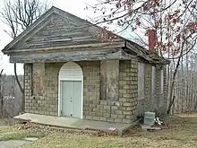 Color photograph of the cemetery chapel seen in the film, now with all windows boarded over.