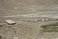 A view of Everest North Base Camp looking west, August 3, 2002. The permanent structure at left is for mountain climbers, central-left structure is for pit toilets, while the temporary wood-frame, plastic tarpaulin-covered structures below and right are for other visitors and support people