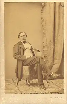 Photograph of Félix Milliet, posing cross-legged on a chair.