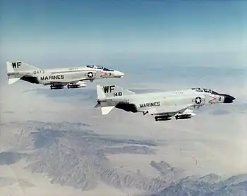 A pair of armed Phantom jet fighters in flight at high altitude