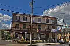 The front of an inn, three stories high, with a balcony on the second floor.