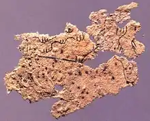 Fragment of ancient Chinese paper map with features in black ink, found on the chest of the occupant of Tomb 5 of Fangmatan, Gansu in China in 1986, from early Western Han, 2nd century BC, 5.6 cm × 2.6 cm (2.2 in × 1.0 in).