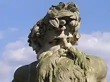 A photograph of the head and shoulders of the statue – a heavily bearded man crowned with foliage