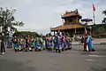 People in formal mandarin official uniforms walking in a parade.